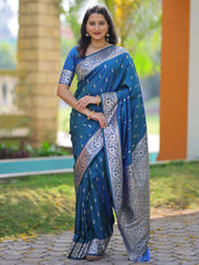 Woman wearing a blue saree with white patterns standing outdoors.