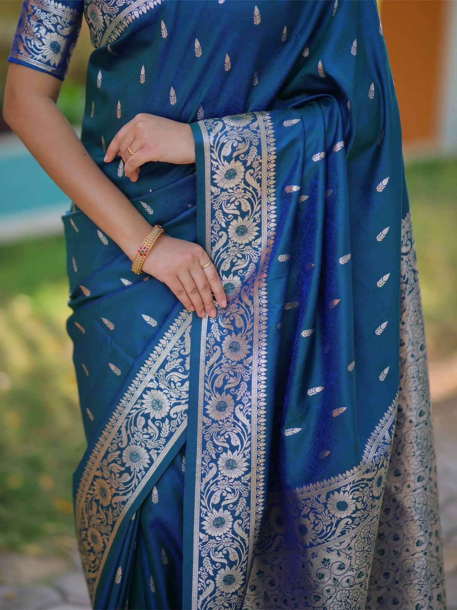 Blue saree with white patterns held by a person outdoors