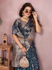 Woman wearing a traditional saree with a decorative bag against a pink wall.