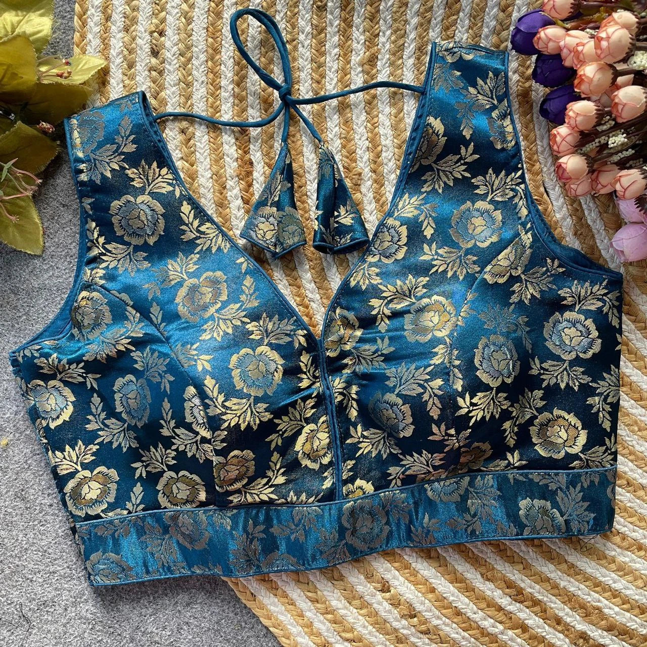 Blue floral-patterned top on a textured surface with flowers in the background