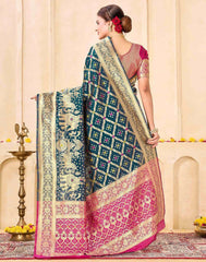 Woman wearing a traditional saree with intricate patterns in a decorated indoor setting