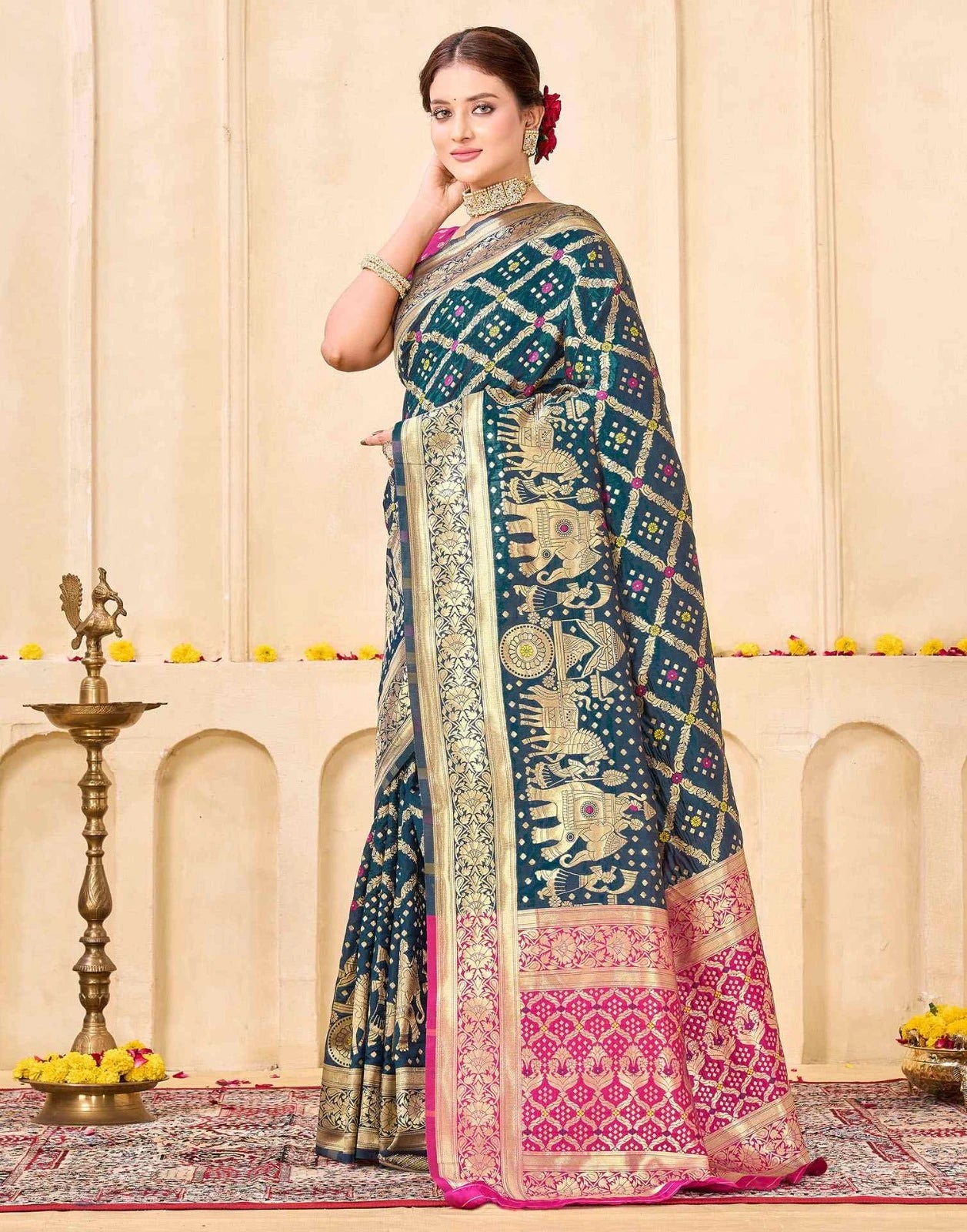 Woman wearing a traditional saree with intricate patterns in a decorated indoor setting.