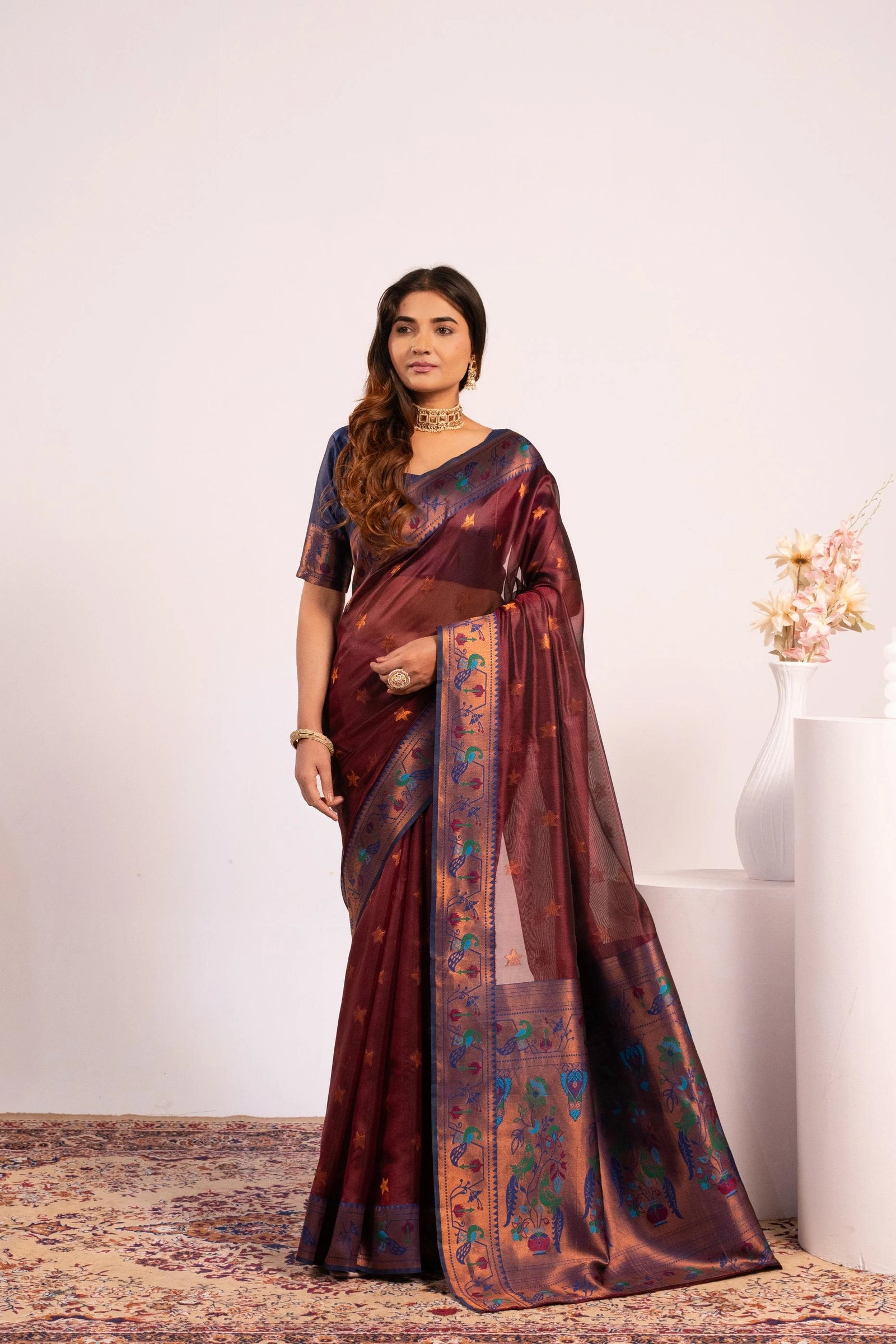 Woman wearing a maroon saree with a floral pattern on a white background