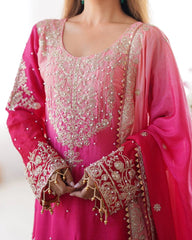 Pink embroidered traditional outfit with gold details on a white background