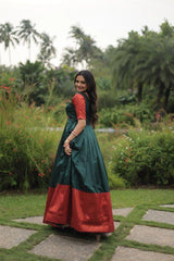 Woman in a green and red traditional outfit standing in a garden.