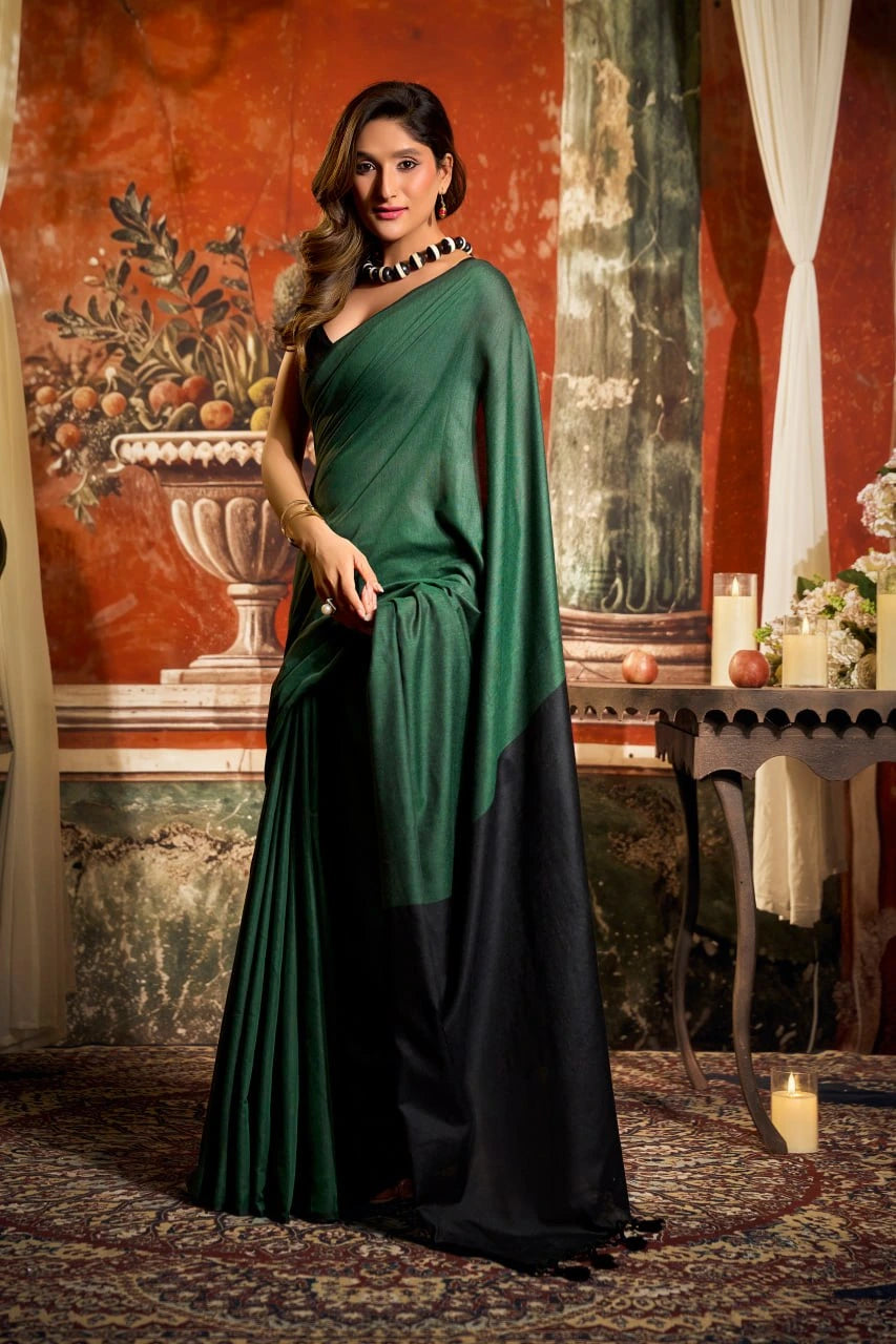 Woman in a green and black saree standing in an ornate room with classical art and decor.