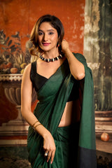 Woman in a green saree with a black blouse against an artistic background