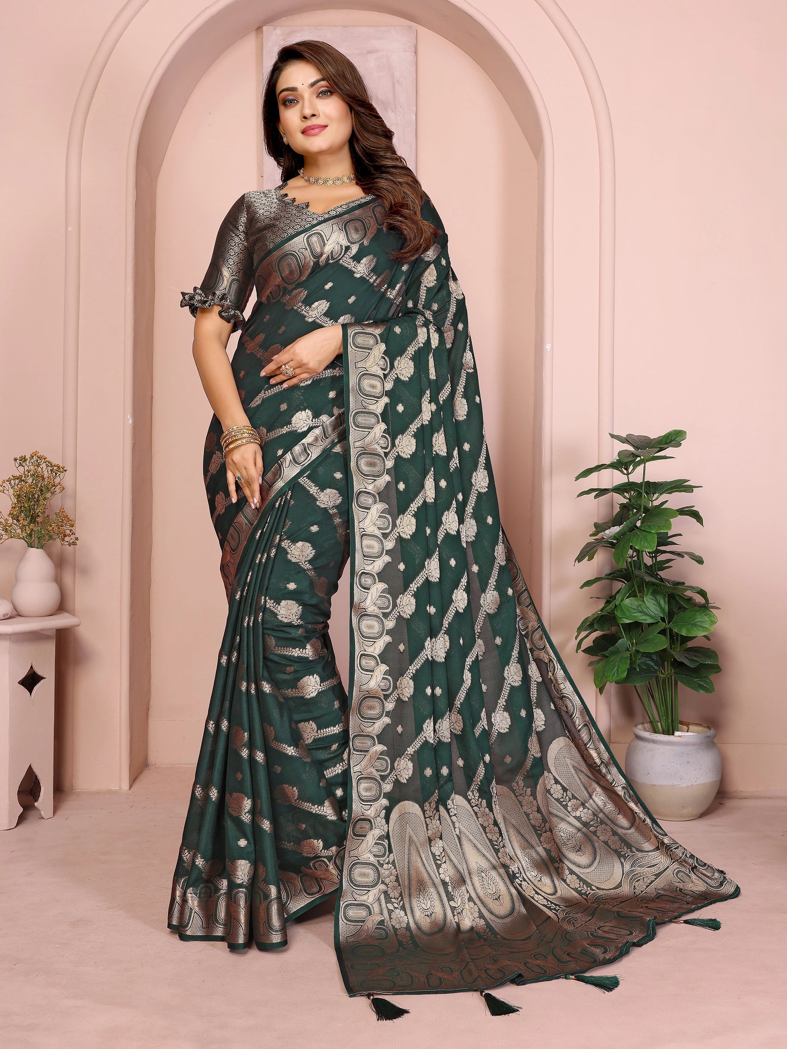 Woman wearing a green saree with a white border in an elegant indoor setting.