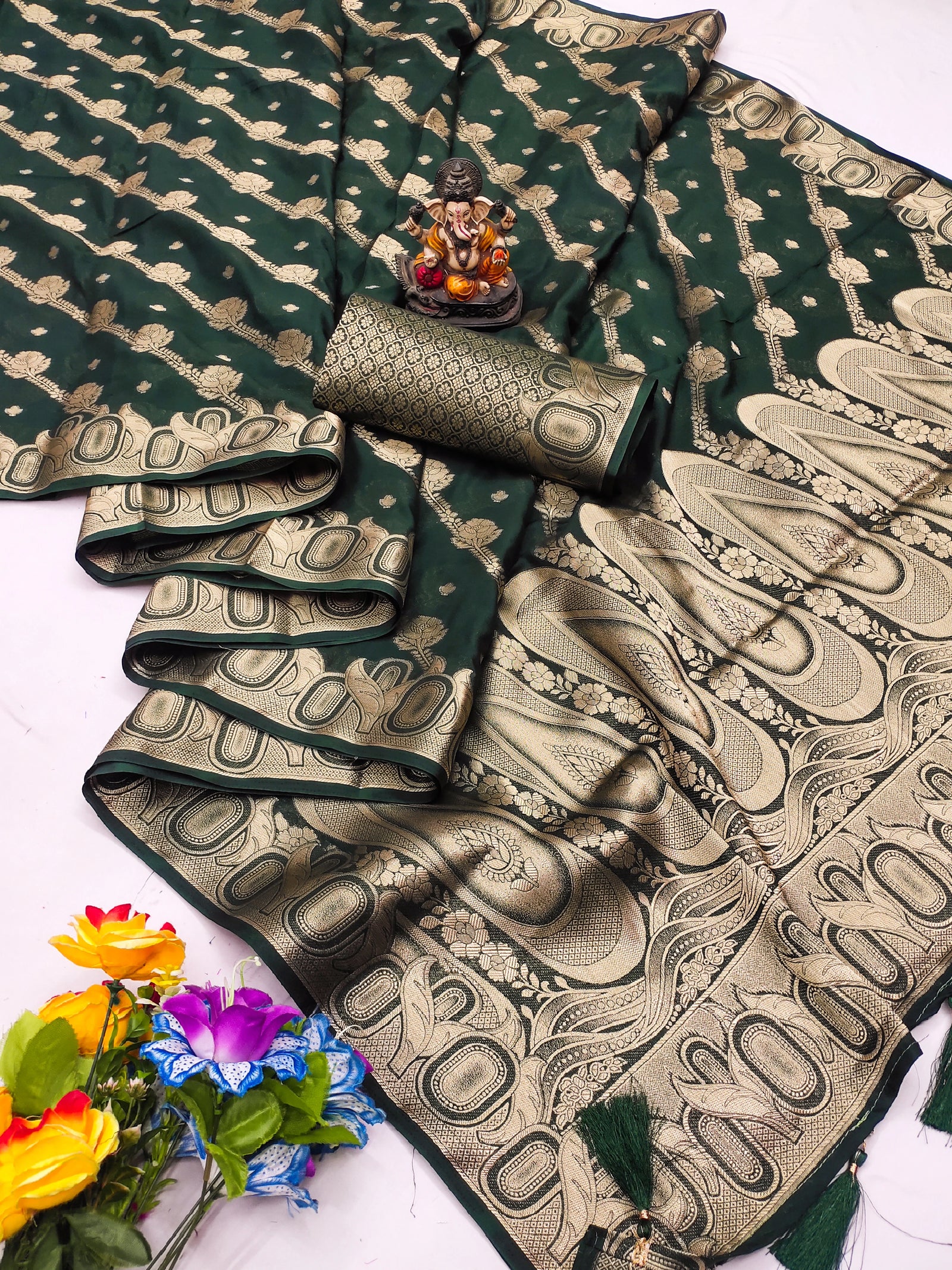 Green and gold saree with floral decorations on a white background