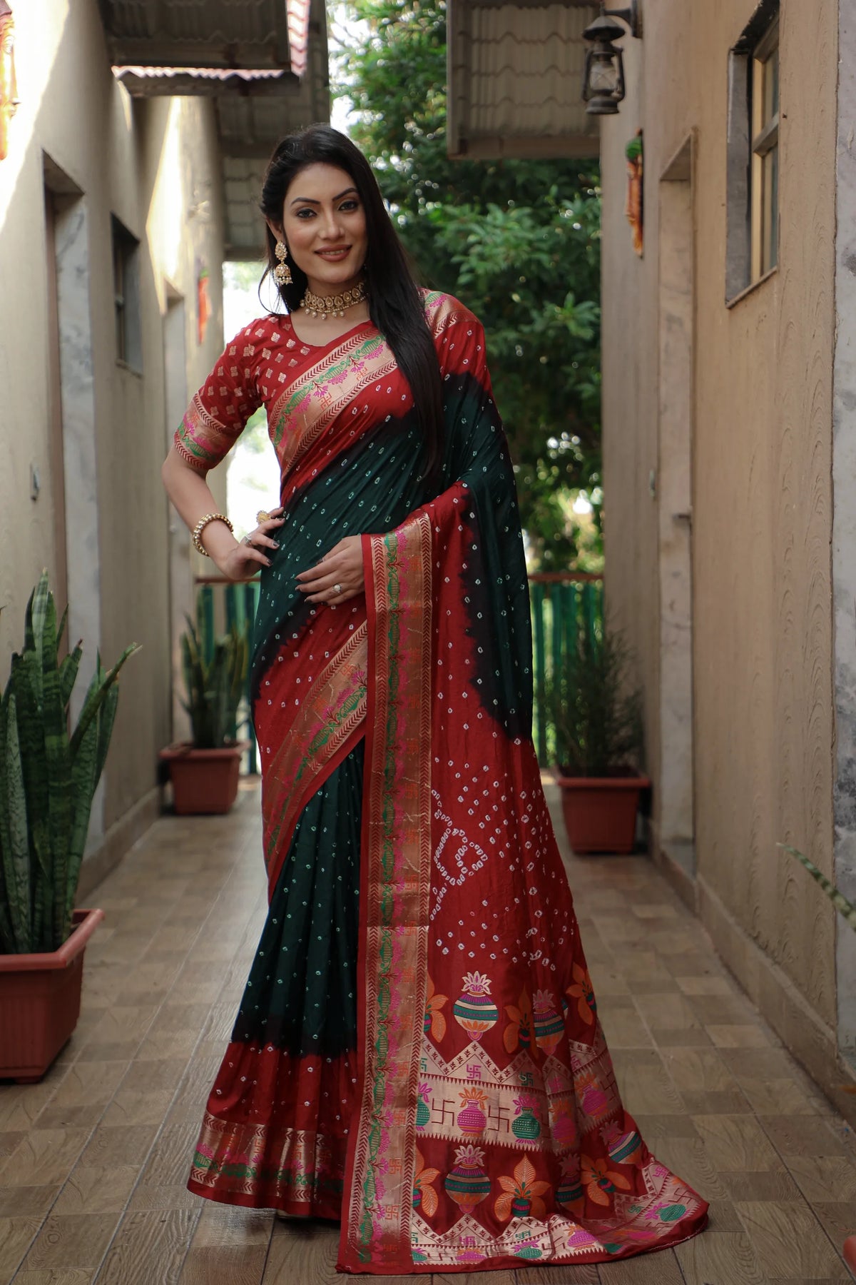 Woman wearing a red and black saree with a traditional design in an outdoor setting.