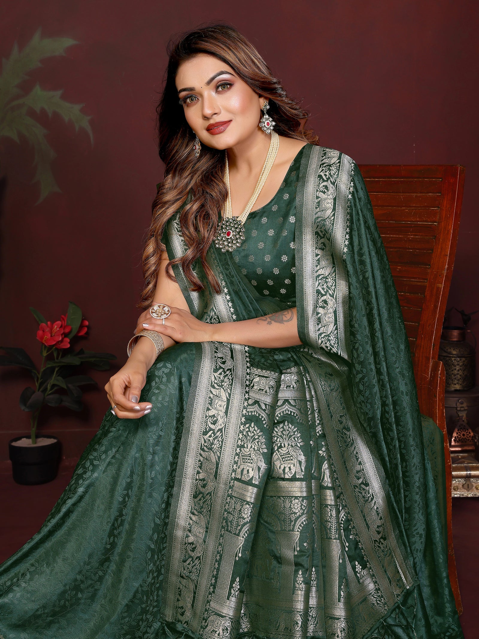 Woman wearing a green saree with silver patterns in a room setting.