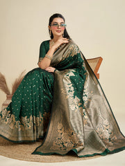 Woman wearing a green and gold saree with floral patterns on a beige background