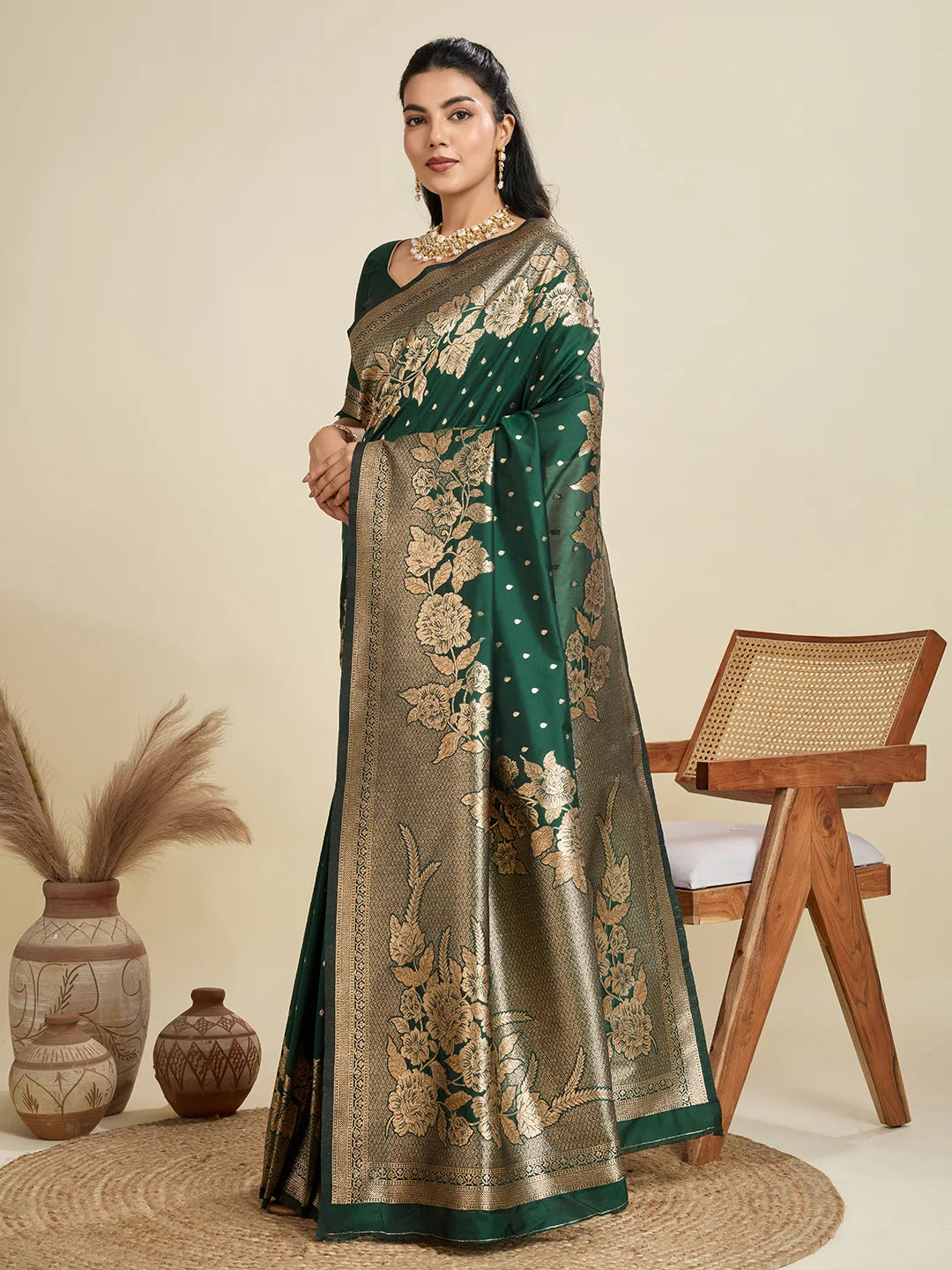 Woman wearing a green and gold saree with floral patterns in a minimalistic setting.