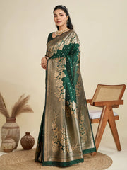 Woman wearing a green and gold saree with floral patterns in a minimalistic setting.