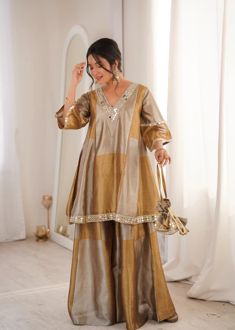 Woman wearing a traditional outfit with gold and beige colors in a softly lit room.