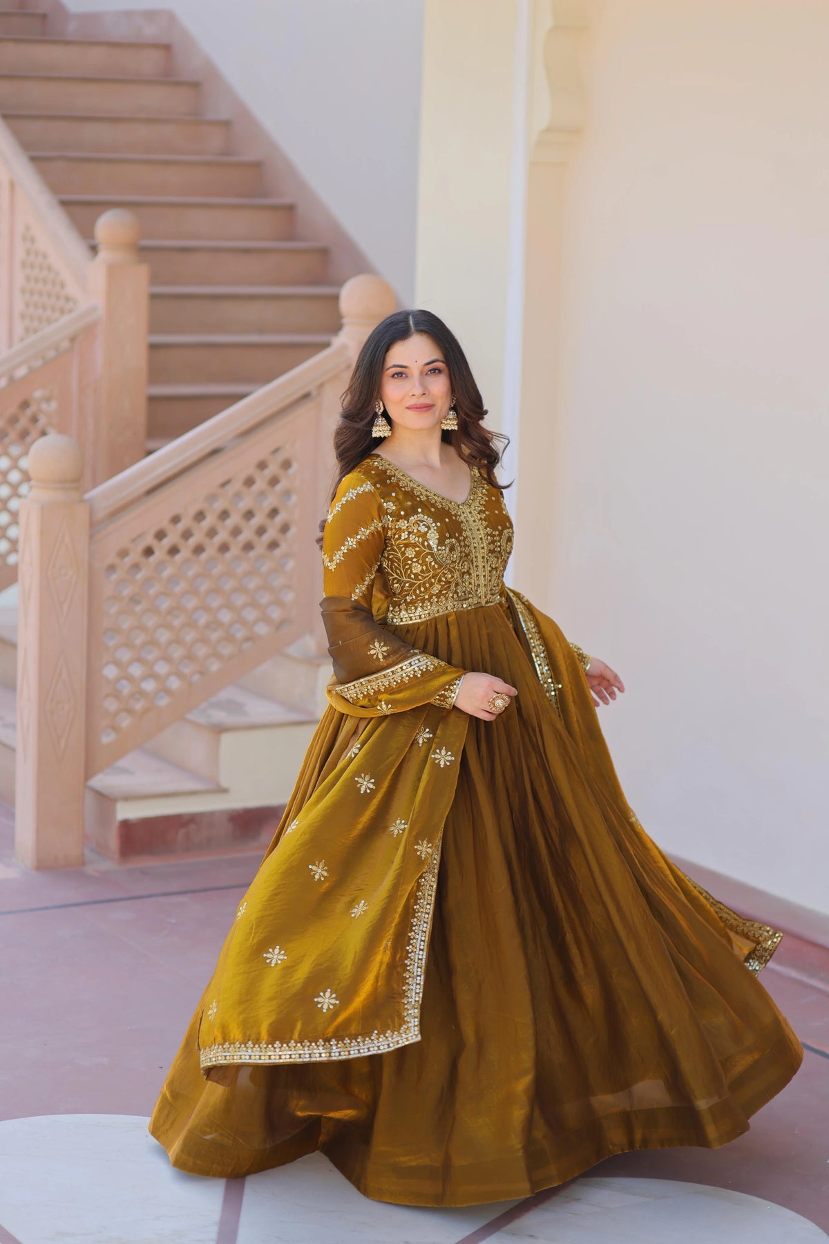 Woman in a mustard yellow traditional outfit standing on a staircase.