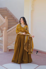 Woman in a mustard yellow traditional outfit standing in a staircase interior.