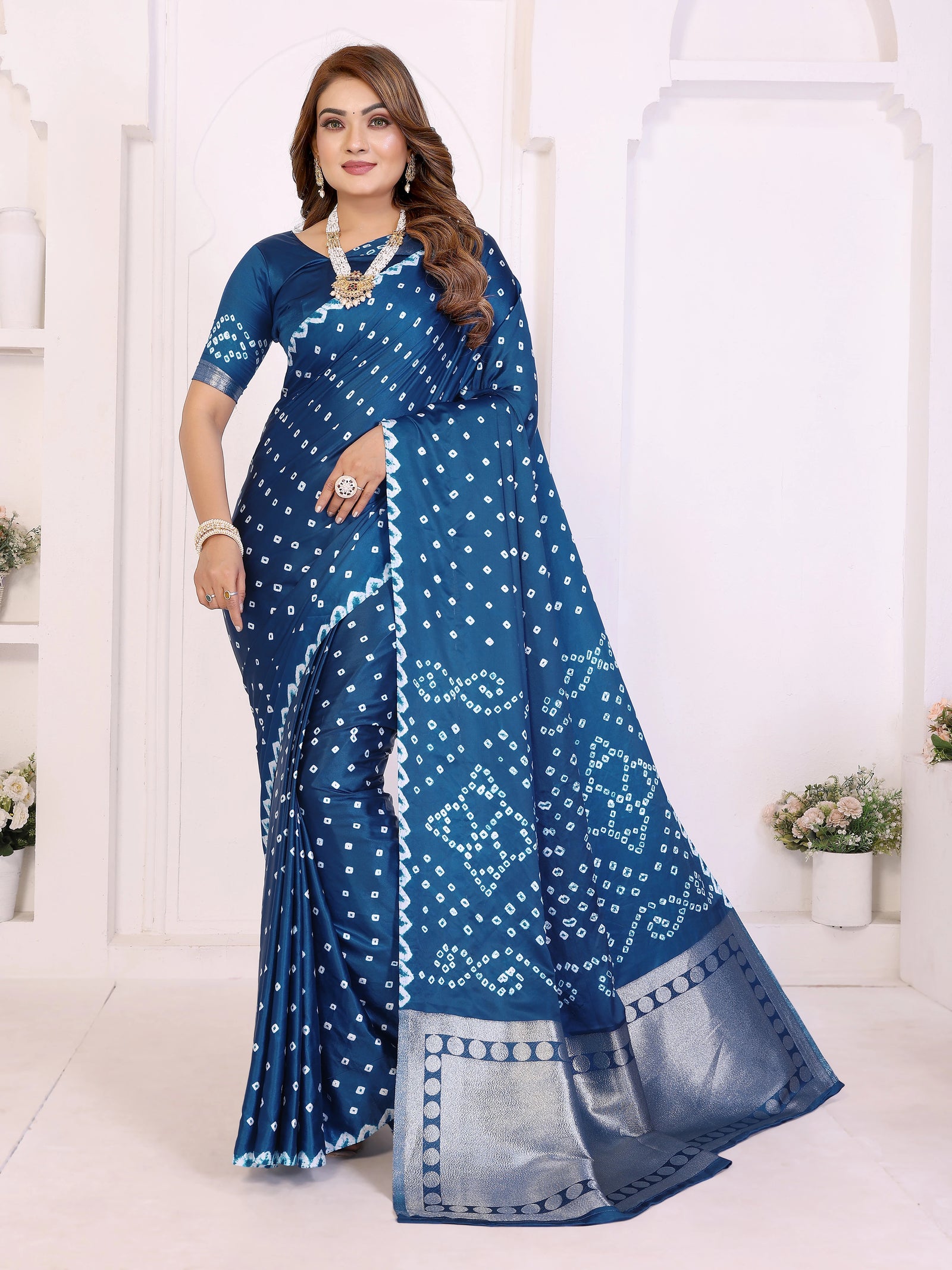 Woman wearing a blue saree with white patterns in a white room.