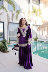 Woman in a purple dress with silver details standing by a pool.