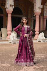 Woman in a purple traditional outfit standing in an ornate outdoor setting.