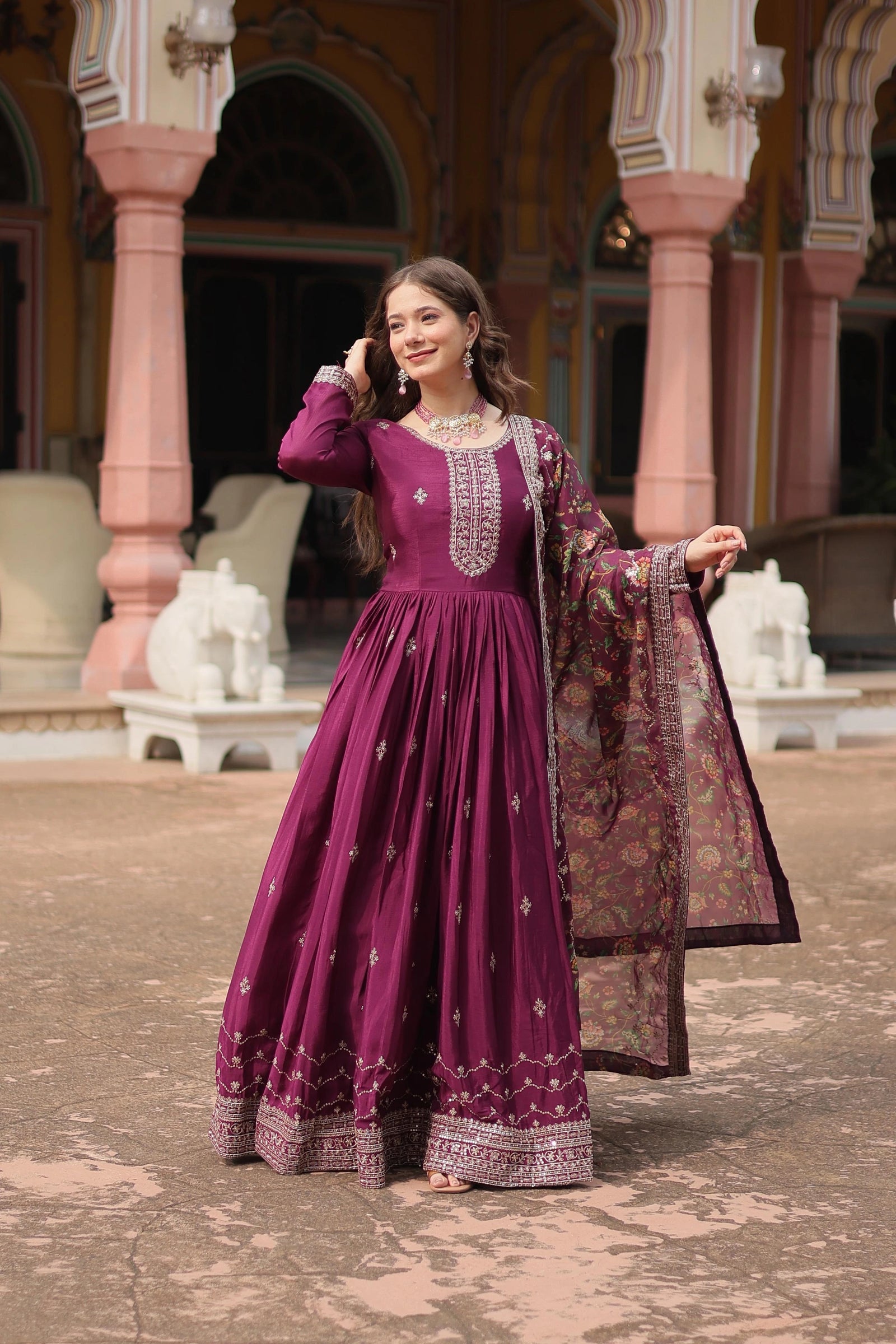 Woman in a purple traditional outfit standing in front of ornate architecture.