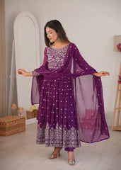 Woman wearing a purple traditional outfit with white patterns in a room.