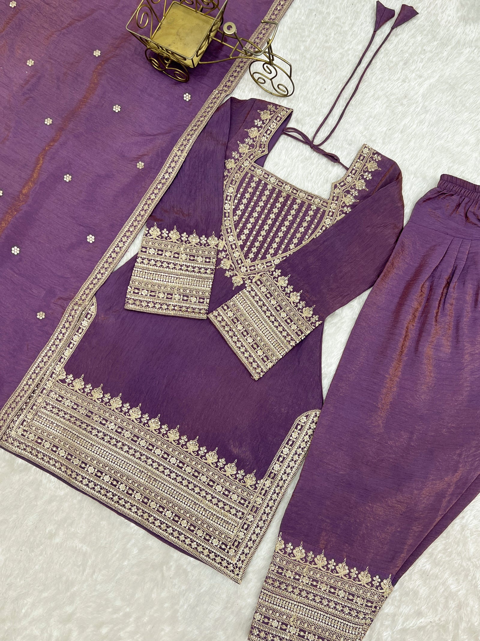 Purple traditional outfit with gold embroidery on a textured surface
