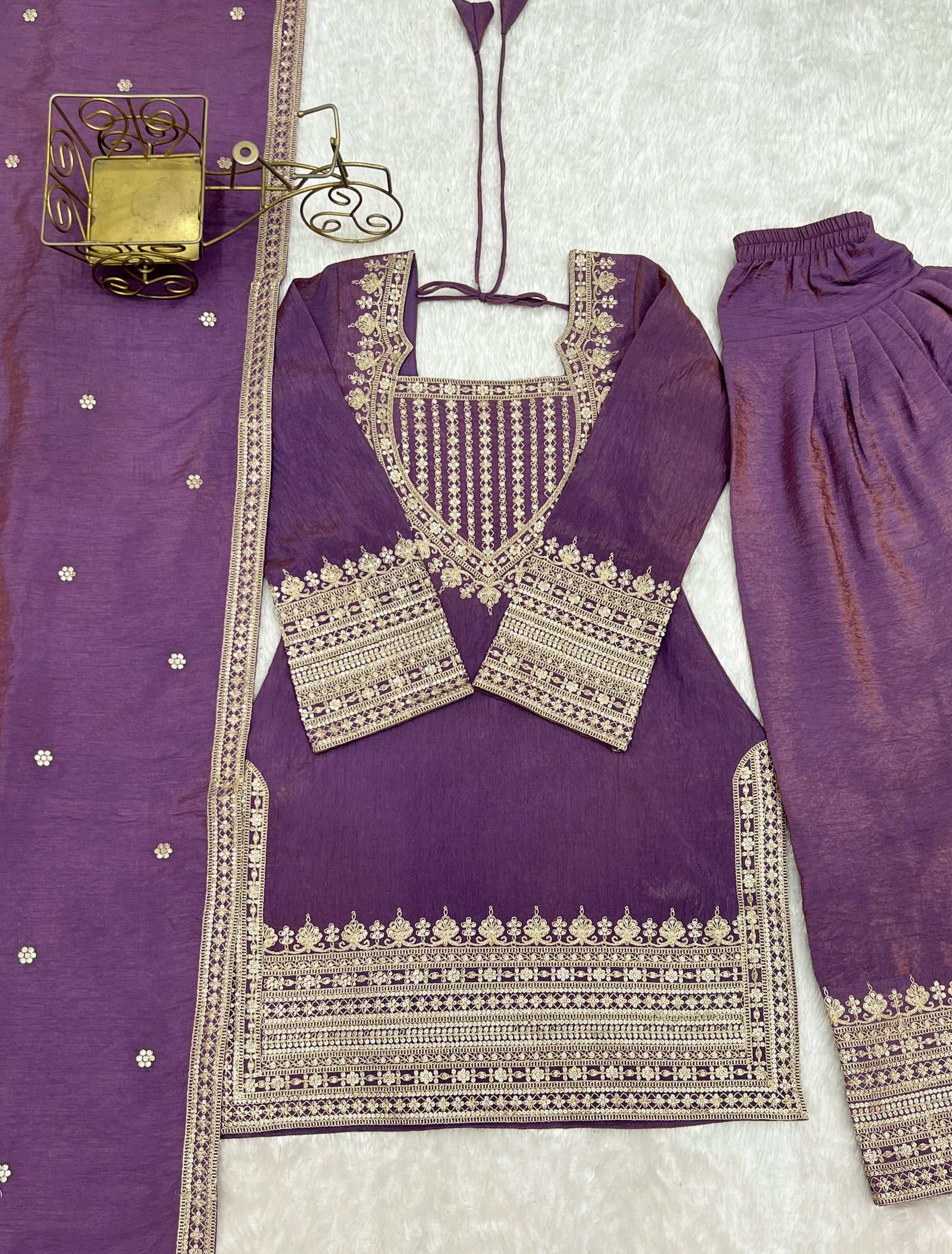 Purple traditional outfit with intricate silver embroidery on a light gray background