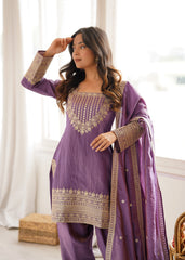 Woman wearing a purple traditional outfit with gold embroidery indoors.