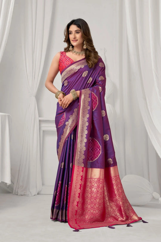 Woman wearing a purple and pink saree with a white curtain background
