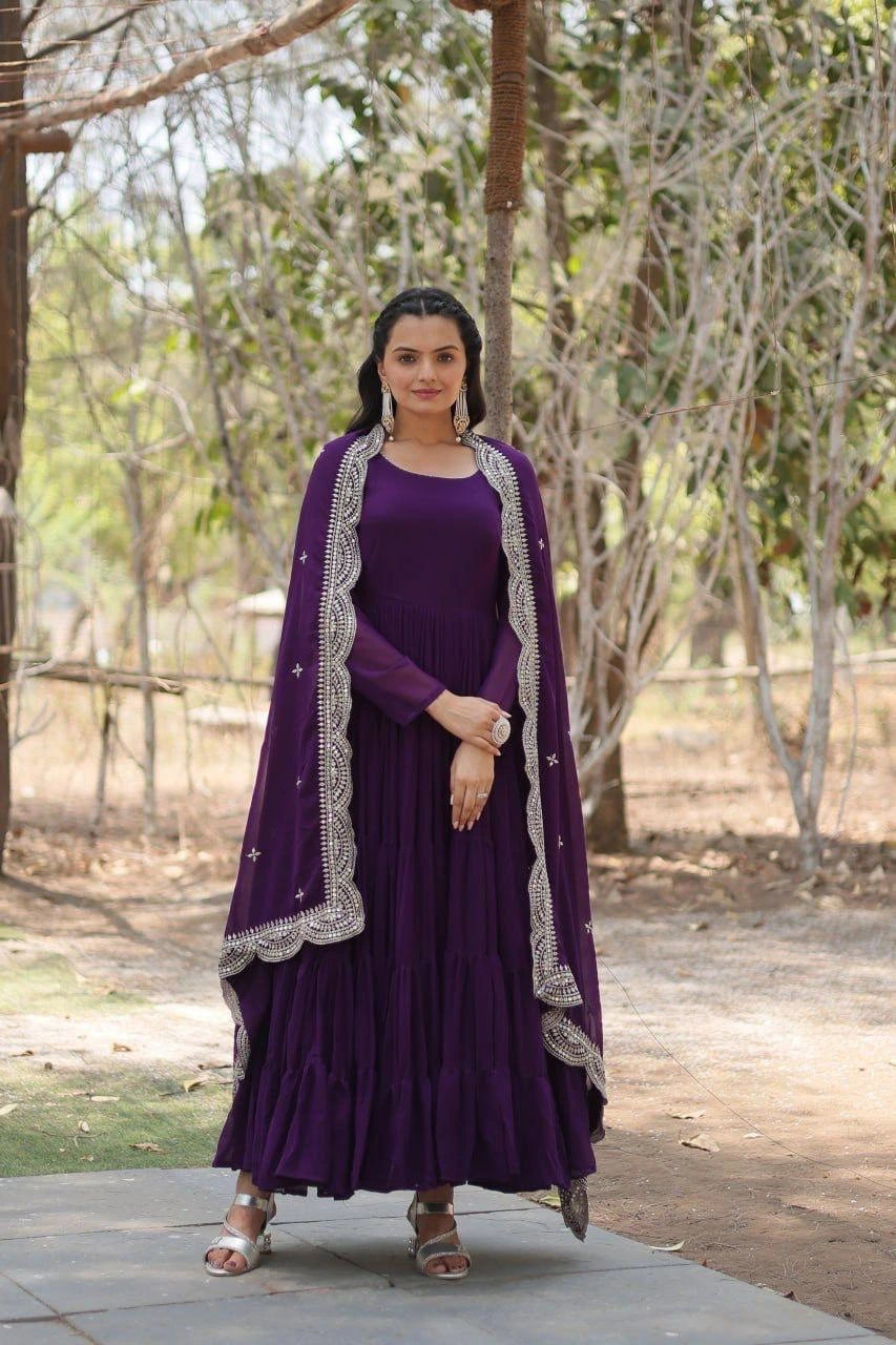 Woman in a purple traditional outfit with a matching dupatta standing outdoors.