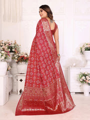 Woman wearing a red saree with white patterns in a decorated room.