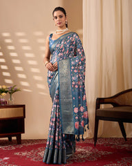 Woman wearing a floral saree standing in a room with a beige wall and red carpet.
