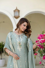 Woman in a light blue embroidered outfit standing outdoors with floral decorations.
