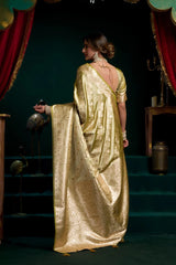Woman in a gold saree standing on a stage with red curtains.