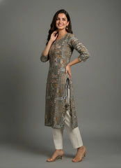 Woman wearing a patterned long shirt and light pants on a gray background