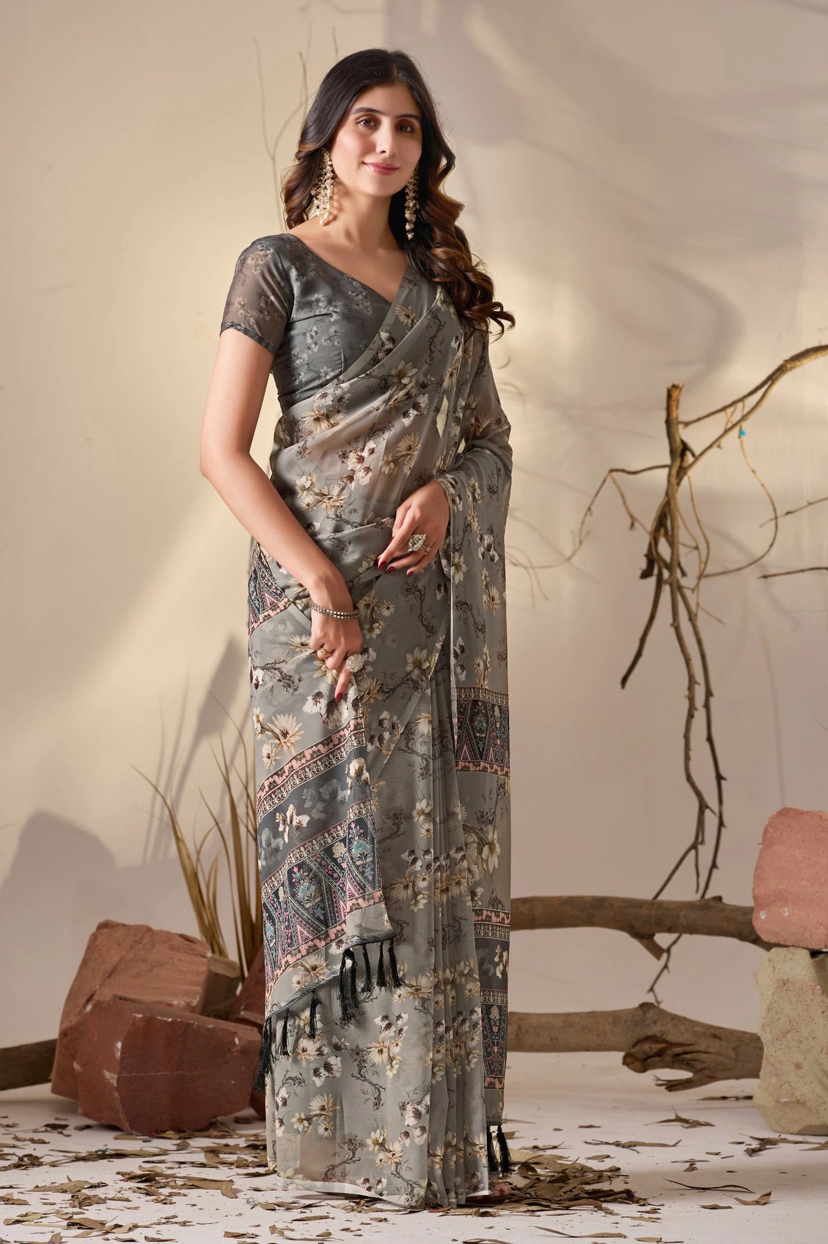 Woman wearing a gray saree with a subtle pattern against a neutral background