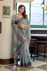Woman wearing a gray saree with colorful patterns in an indoor setting.