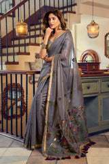 Woman in a gray saree with floral patterns indoors