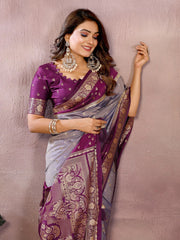 Woman wearing a purple and gray saree with intricate patterns against a plain background