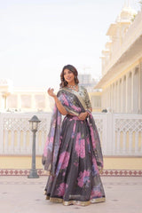 Woman in a floral saree standing in front of a traditional building.
