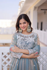 Woman in traditional outfit with intricate patterns standing outdoors.