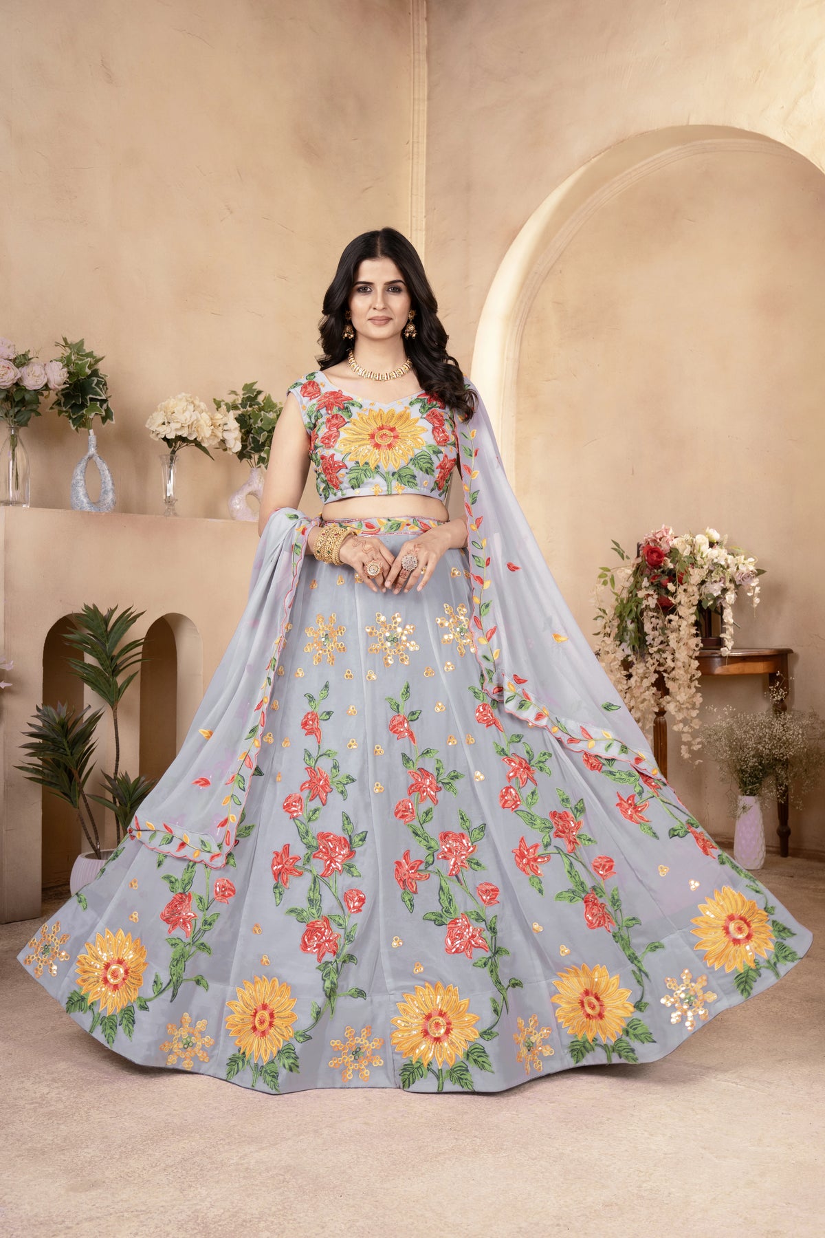 Woman wearing a floral embroidered lehenga in a decorated indoor setting
