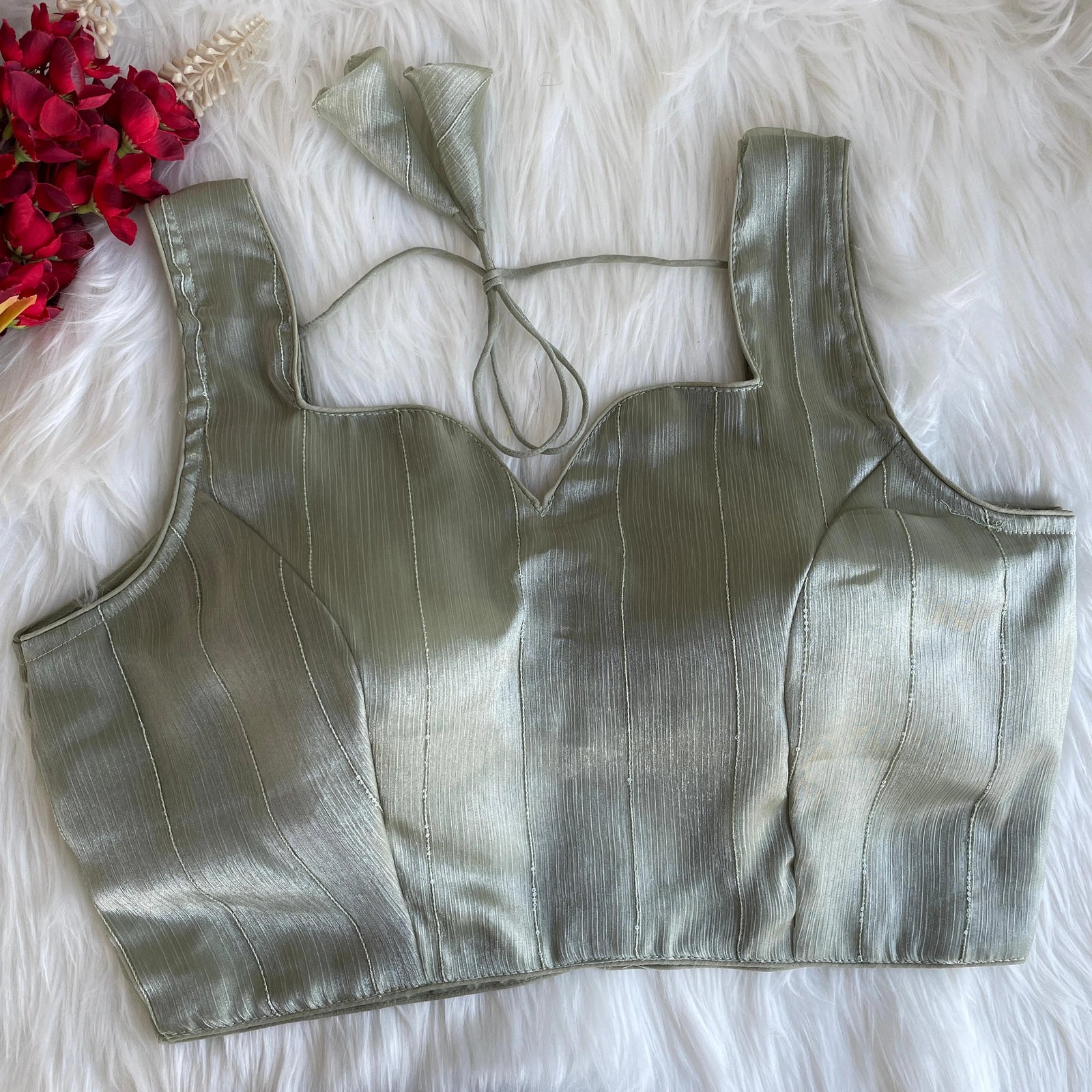 Silver metallic top on a white fur surface with red flowers.