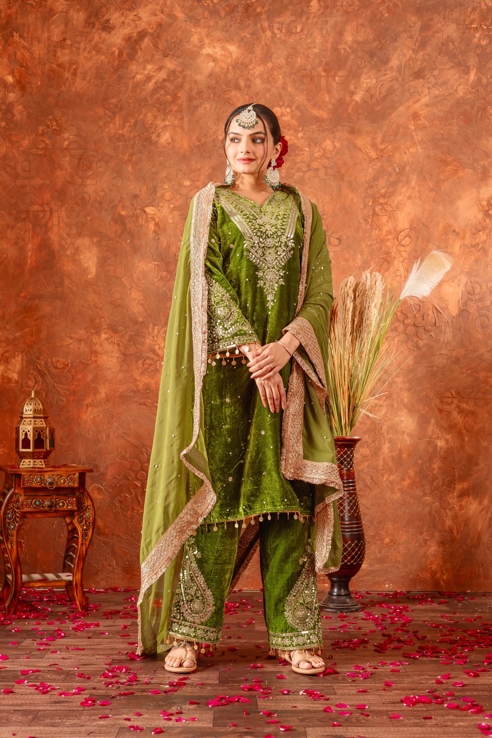 Woman in traditional green and gold outfit with a textured brown background