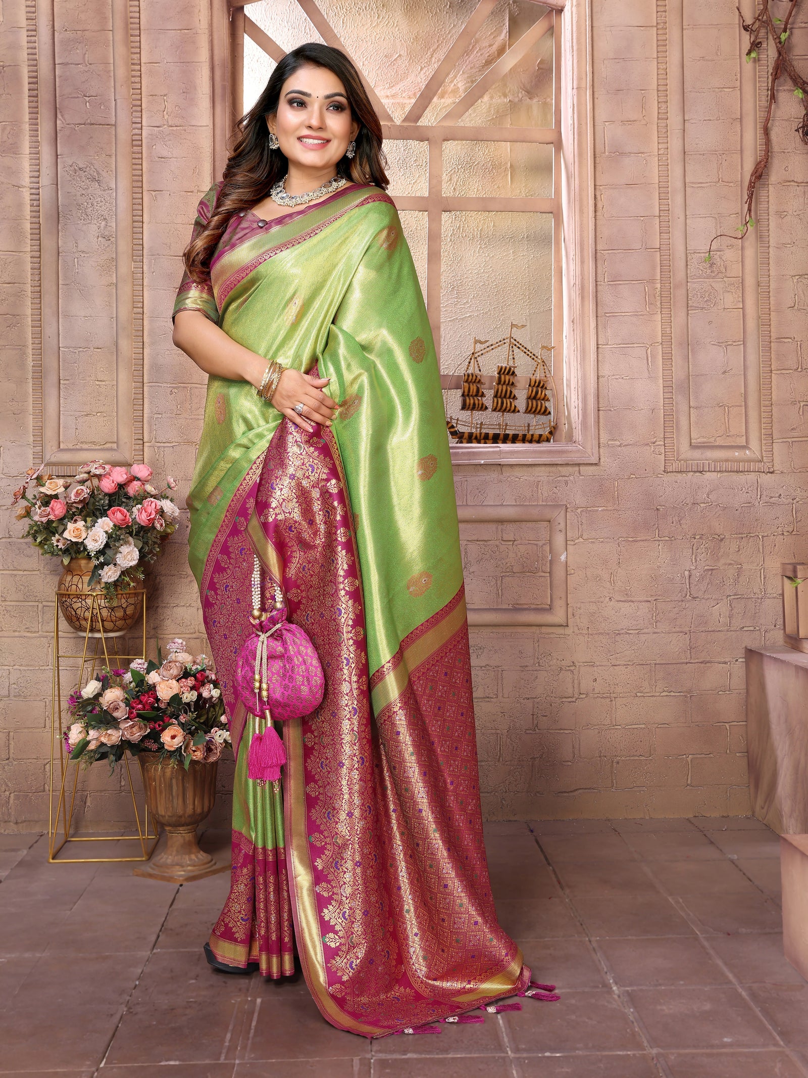 Woman wearing a green and pink saree with a floral arrangement in the background