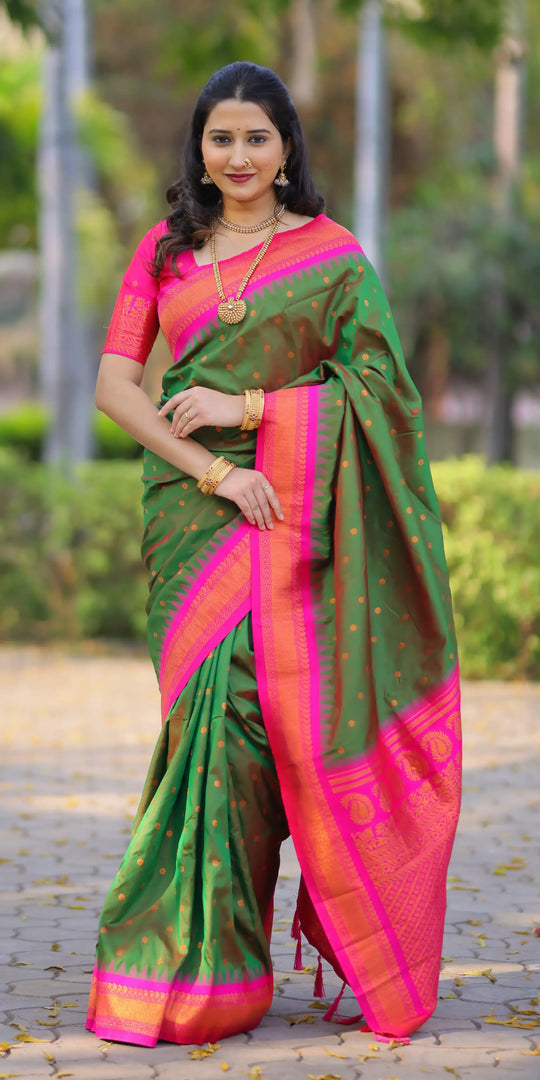 Woman wearing a green and pink saree with a blurred outdoor background
