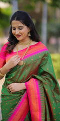 Woman wearing a green and pink saree with gold jewelry outdoors.