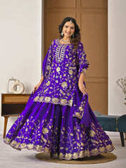 Woman wearing a purple traditional outfit with gold embroidery in a room setting.