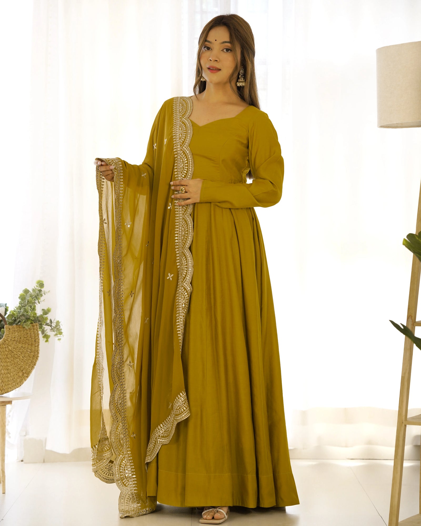 Woman wearing a mustard yellow traditional outfit with a white background
